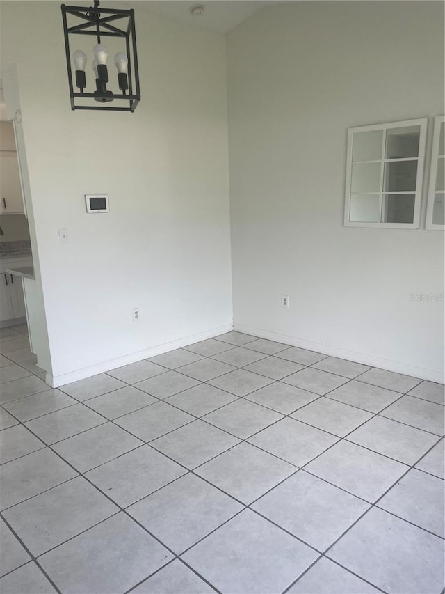 spare room featuring an inviting chandelier and light tile patterned floors