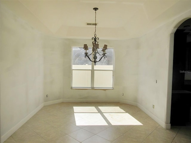 unfurnished dining area featuring visible vents, a tray ceiling, arched walkways, an inviting chandelier, and baseboards