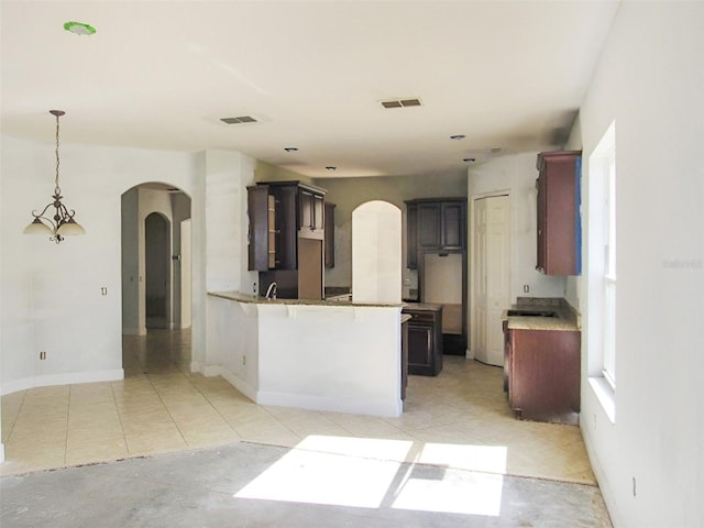 kitchen featuring light tile patterned floors, visible vents, arched walkways, and a peninsula