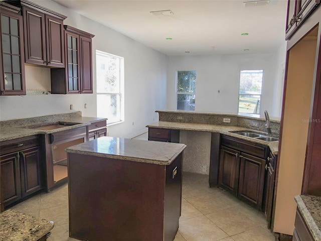 kitchen with light tile patterned floors, a center island, a wealth of natural light, and a sink