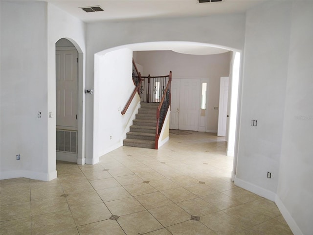 spare room with stairway, arched walkways, visible vents, and baseboards