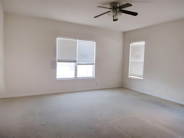 carpeted spare room featuring baseboards and ceiling fan