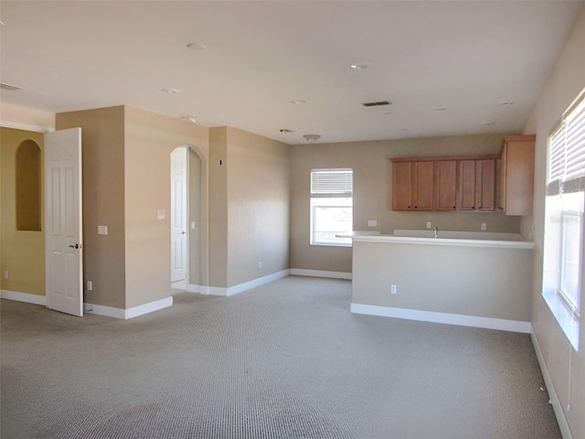 empty room featuring light carpet, visible vents, arched walkways, and baseboards