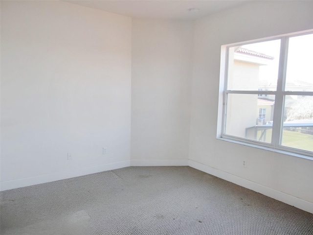 spare room with baseboards and carpet floors