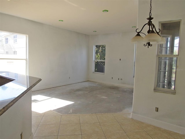 unfurnished room with a notable chandelier, baseboards, and light tile patterned floors