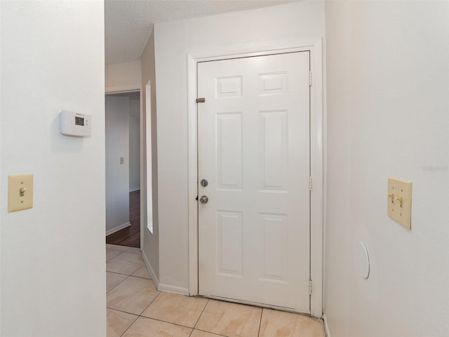 corridor featuring a textured ceiling and light tile patterned floors