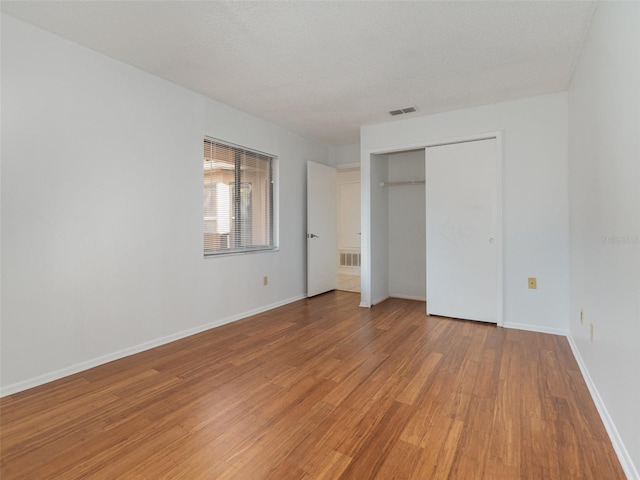 unfurnished bedroom with hardwood / wood-style floors, a textured ceiling, and a closet