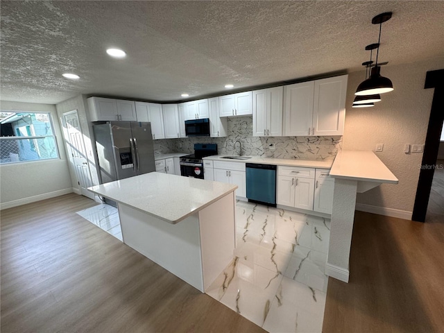 kitchen featuring appliances with stainless steel finishes, decorative light fixtures, tasteful backsplash, sink, and white cabinets