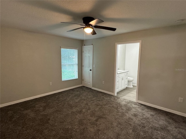 unfurnished room with ceiling fan, dark carpet, and a textured ceiling