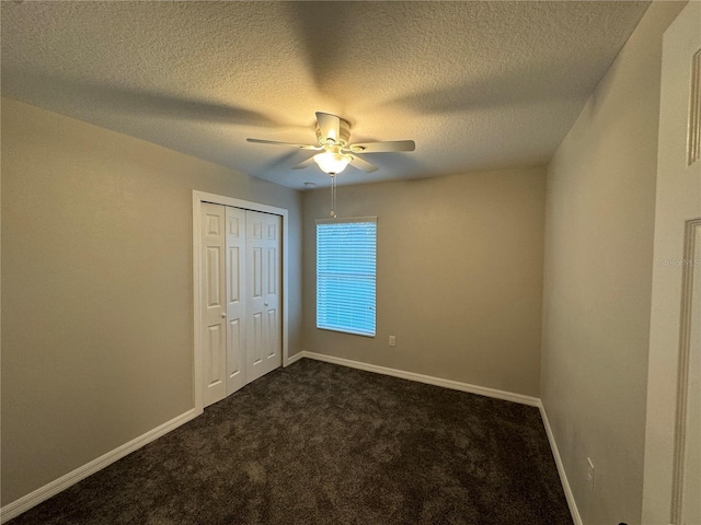 unfurnished bedroom featuring ceiling fan, a textured ceiling, a closet, and dark colored carpet