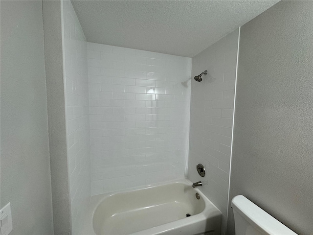 bathroom featuring tiled shower / bath, a textured ceiling, and toilet