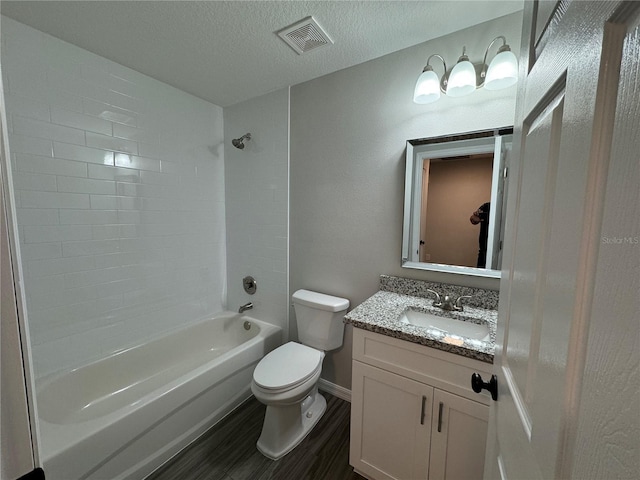 full bathroom featuring vanity, wood-type flooring, a textured ceiling, toilet, and tiled shower / bath