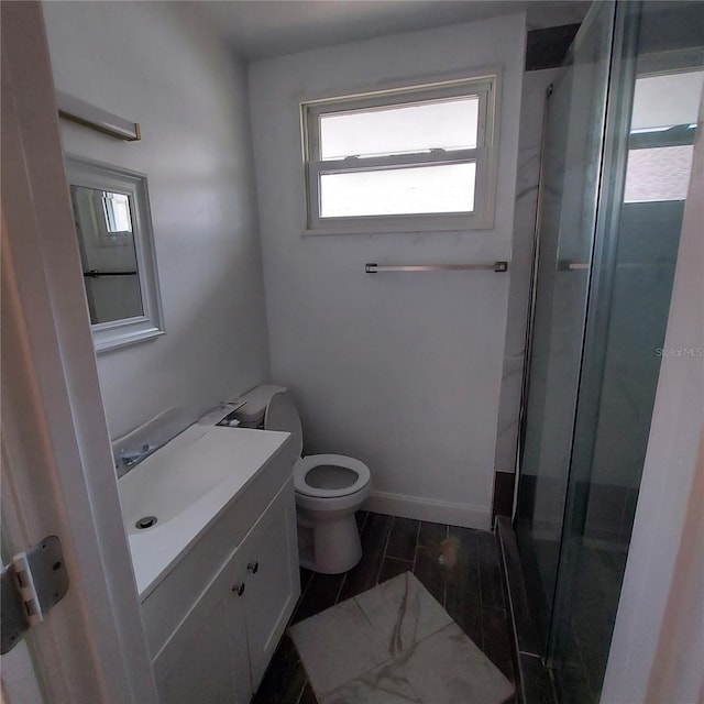 bathroom with a shower with door, vanity, and toilet