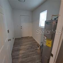 laundry room featuring dark wood-type flooring and electric water heater