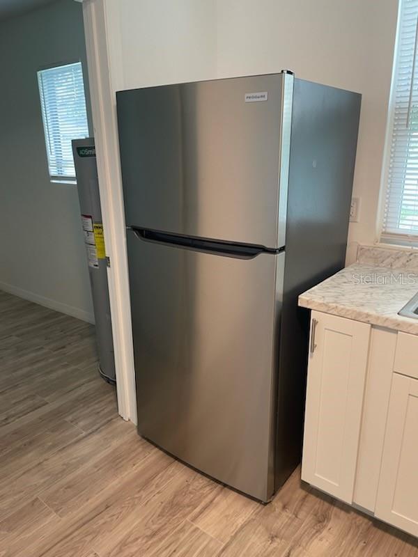 kitchen with white cabinetry, stainless steel refrigerator, and light hardwood / wood-style floors