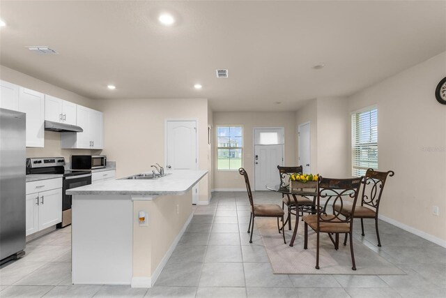 kitchen with appliances with stainless steel finishes, sink, white cabinets, a kitchen island with sink, and light tile patterned floors