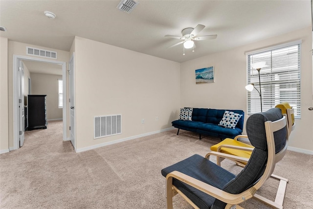 living area featuring light colored carpet and ceiling fan