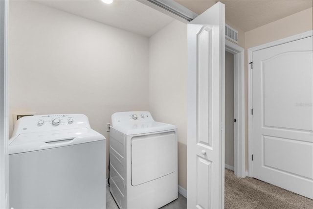 clothes washing area featuring washer and clothes dryer and light carpet