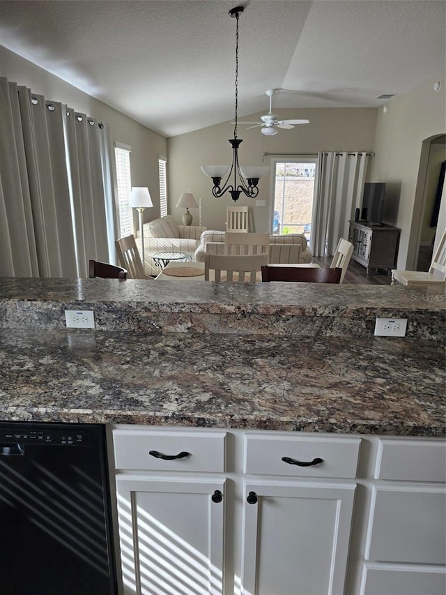 kitchen featuring lofted ceiling, hanging light fixtures, dishwasher, dark stone counters, and white cabinets