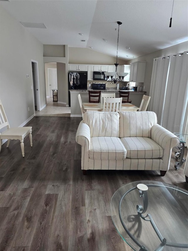 living room with vaulted ceiling, dark wood-type flooring, and a chandelier