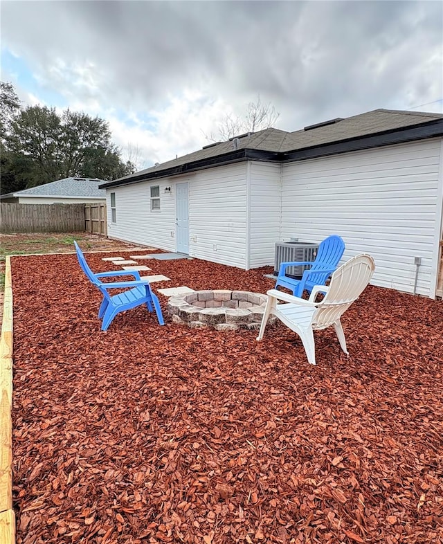 rear view of house featuring central air condition unit and an outdoor fire pit