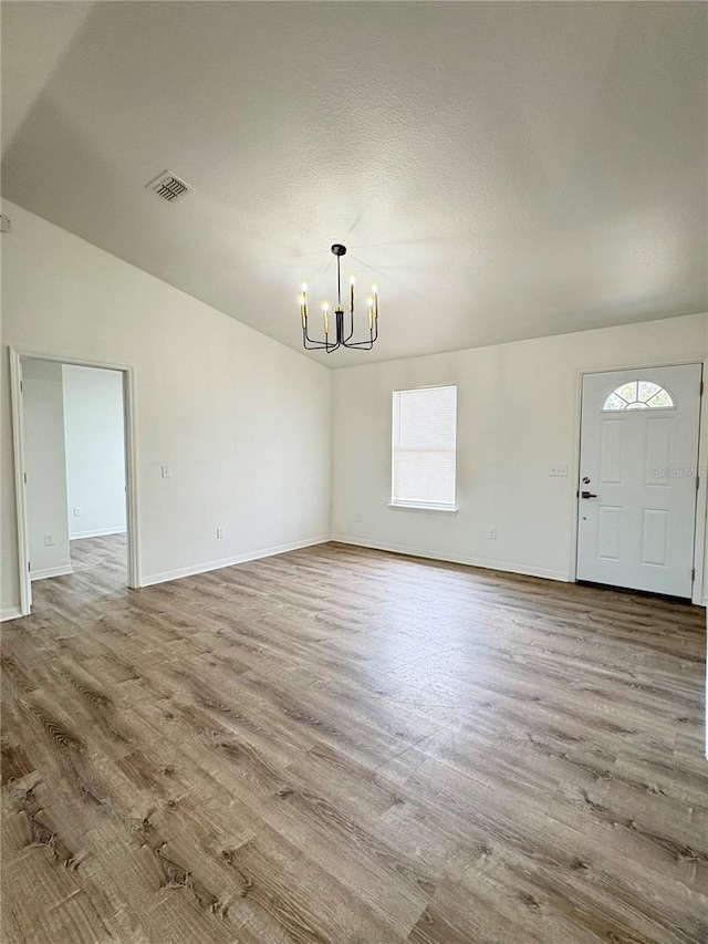 interior space featuring wood-type flooring, vaulted ceiling, a textured ceiling, and a chandelier