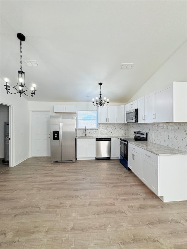 kitchen featuring an inviting chandelier, white cabinetry, stainless steel appliances, and decorative light fixtures