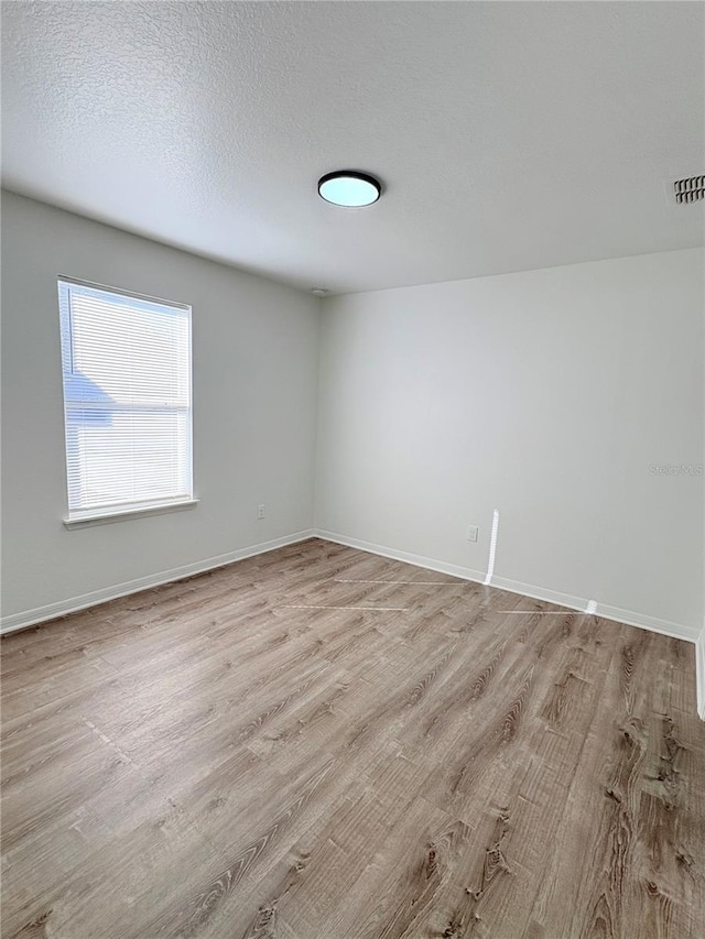 unfurnished room with a textured ceiling and light hardwood / wood-style floors