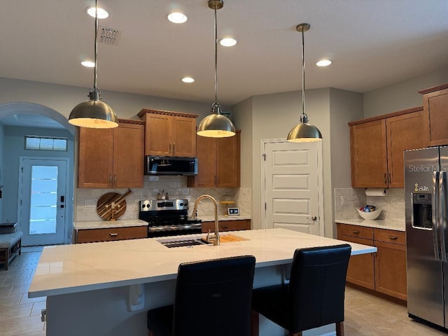 kitchen featuring pendant lighting, stainless steel appliances, and a center island with sink