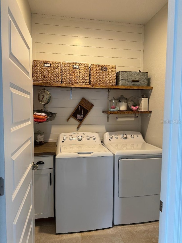 laundry room featuring cabinets, washing machine and dryer, and wood walls