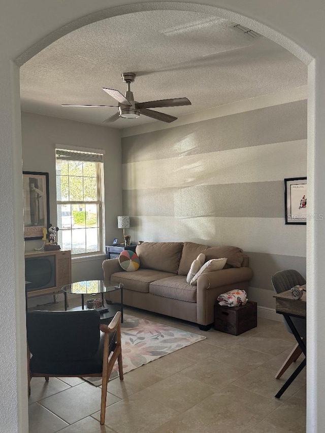 living room featuring light tile patterned flooring, ceiling fan, and a textured ceiling