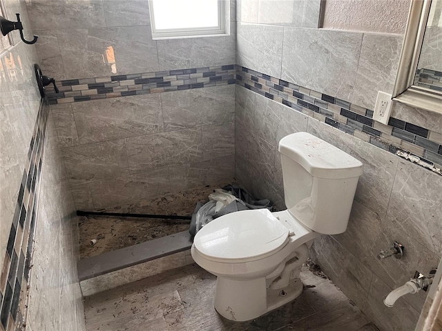 bathroom featuring tile walls, toilet, and tiled shower