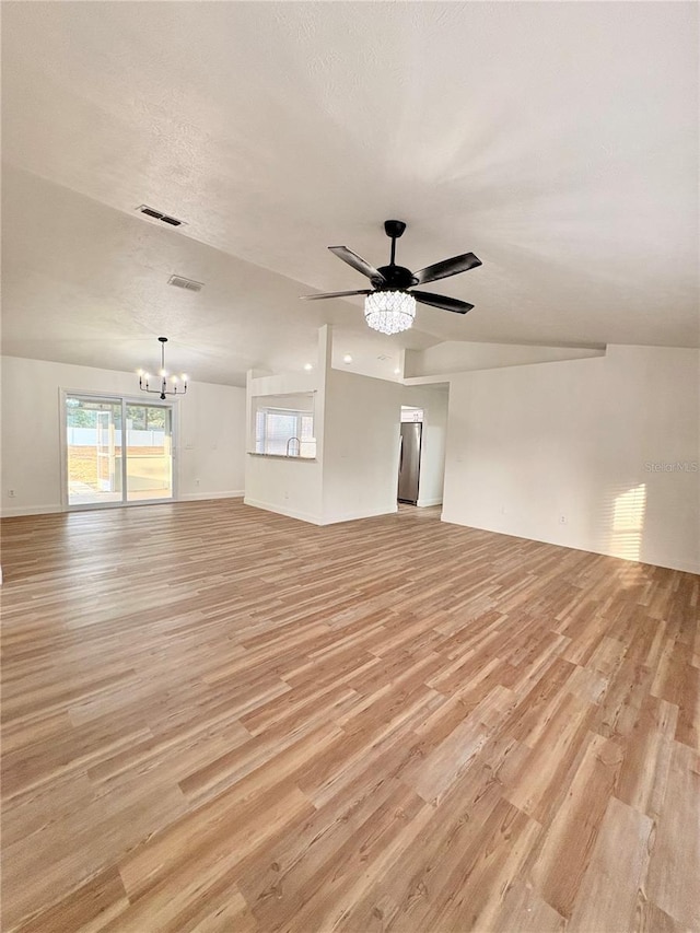 spare room featuring vaulted ceiling, ceiling fan with notable chandelier, a textured ceiling, and light wood-type flooring