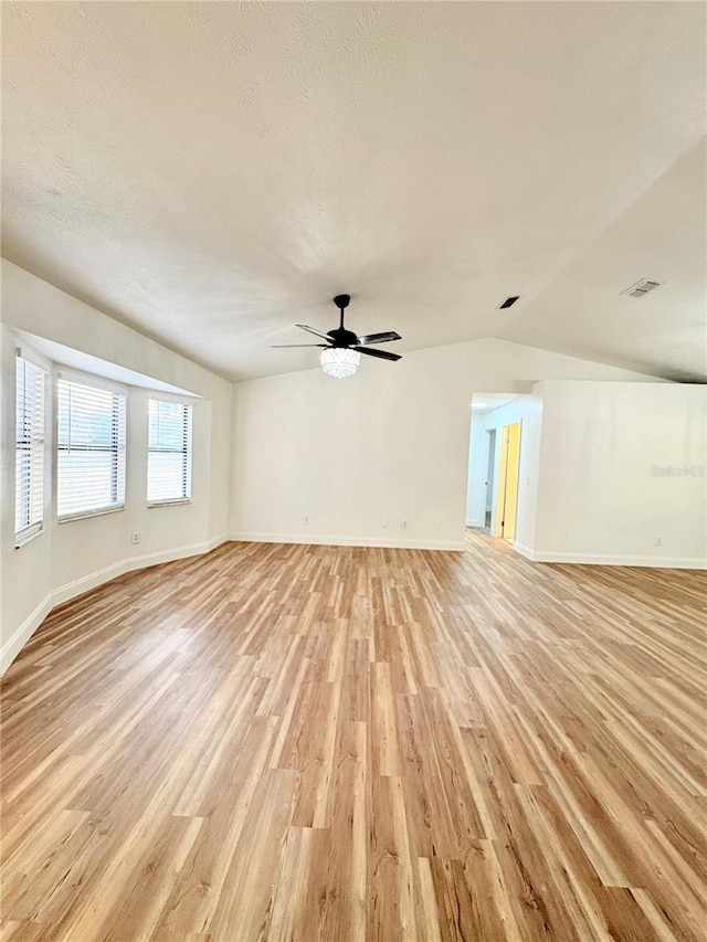 empty room with lofted ceiling, a textured ceiling, ceiling fan, and light hardwood / wood-style flooring