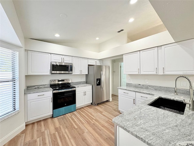 kitchen with appliances with stainless steel finishes, light stone countertops, sink, and white cabinets