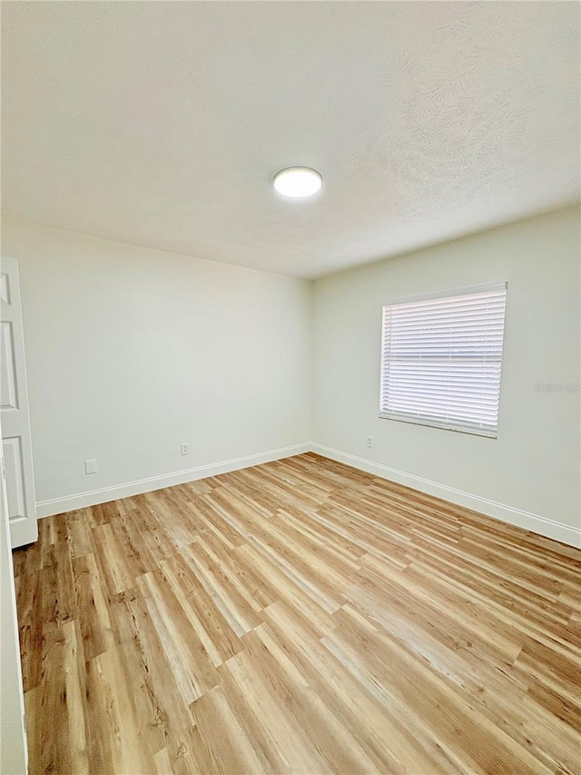 unfurnished room with a textured ceiling and light wood-type flooring