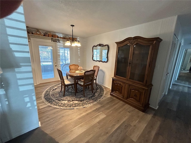 dining room with a textured ceiling, a chandelier, and dark hardwood / wood-style floors