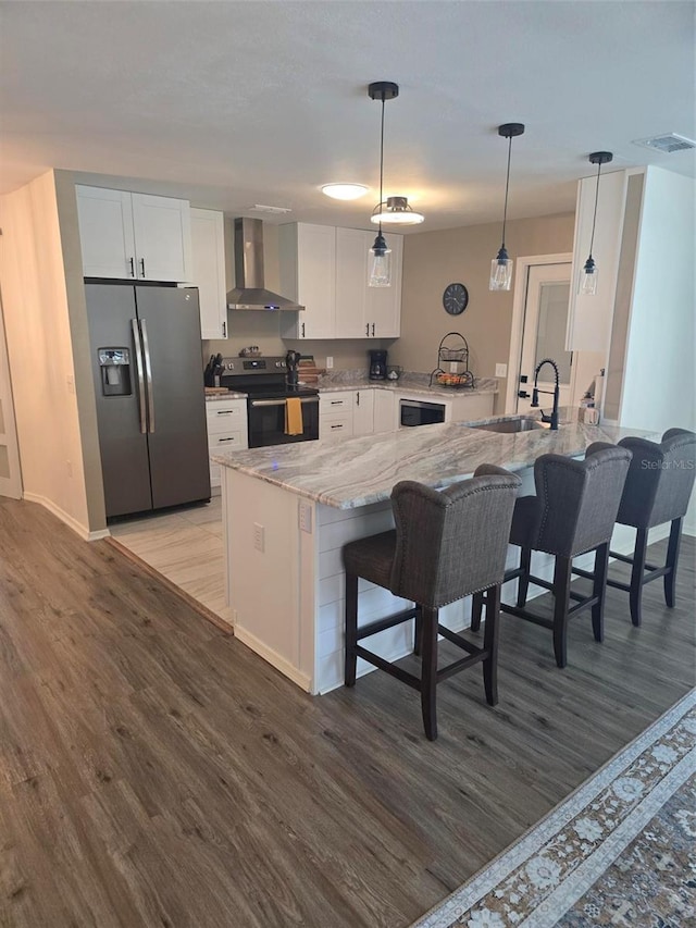 kitchen featuring appliances with stainless steel finishes, decorative light fixtures, white cabinetry, sink, and wall chimney exhaust hood