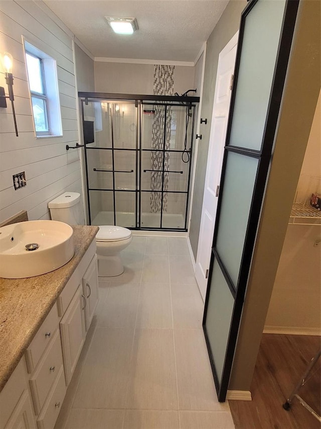 bathroom with toilet, an enclosed shower, wood walls, a textured ceiling, and vanity