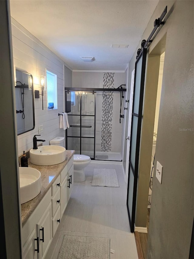 bathroom with vanity, toilet, a shower with shower door, and a textured ceiling