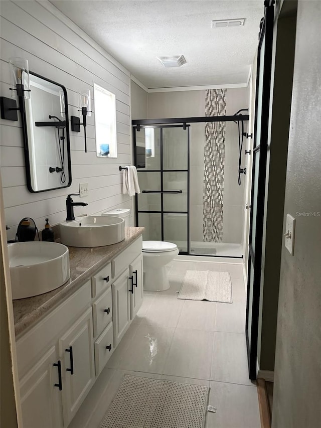 bathroom featuring vanity, a textured ceiling, tile patterned floors, toilet, and walk in shower