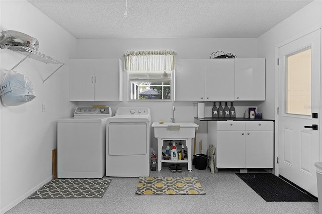 laundry room featuring independent washer and dryer, a textured ceiling, cabinet space, and baseboards