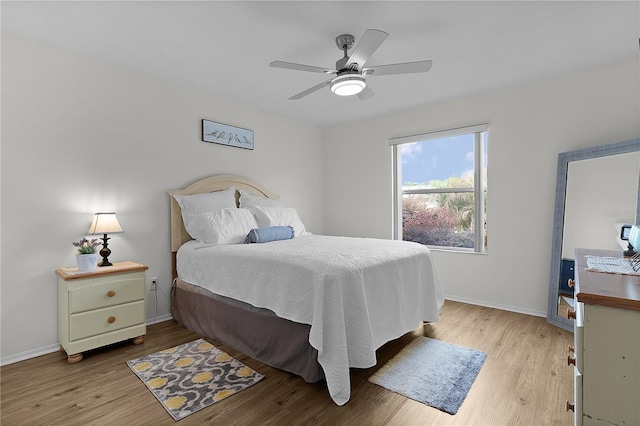 bedroom with light wood-style flooring, baseboards, and ceiling fan