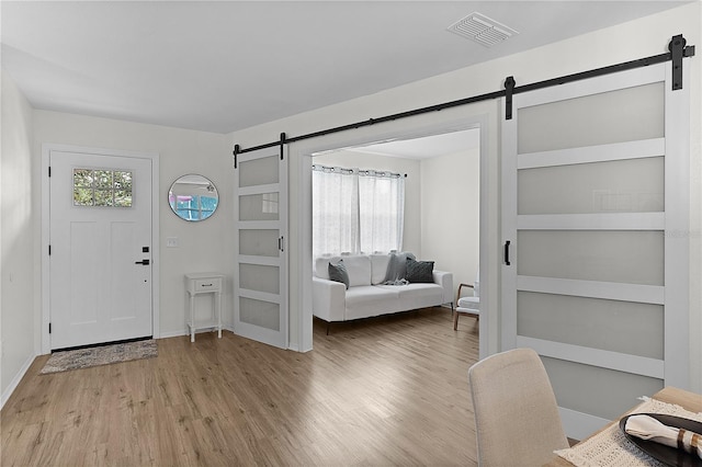 foyer with a barn door, wood finished floors, and baseboards