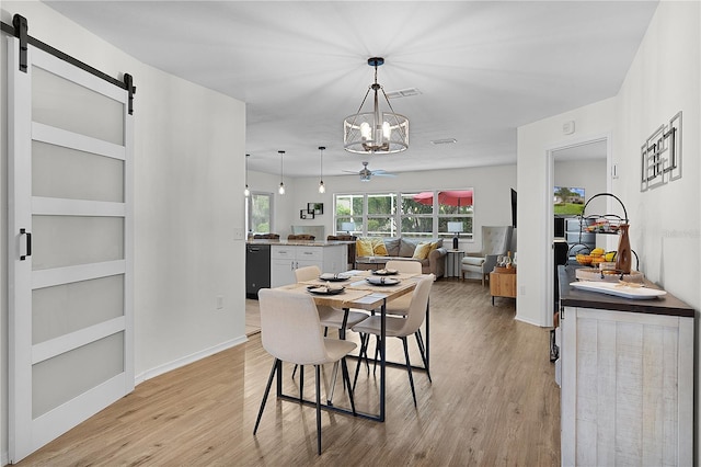 dining space with a barn door, a chandelier, light wood finished floors, and baseboards