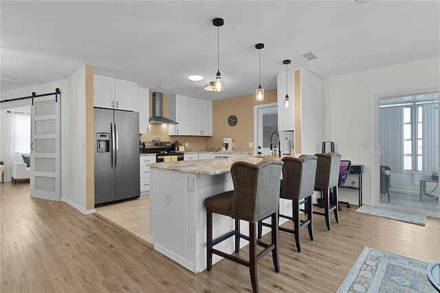 kitchen featuring stainless steel appliances, a peninsula, a barn door, and light wood-style flooring