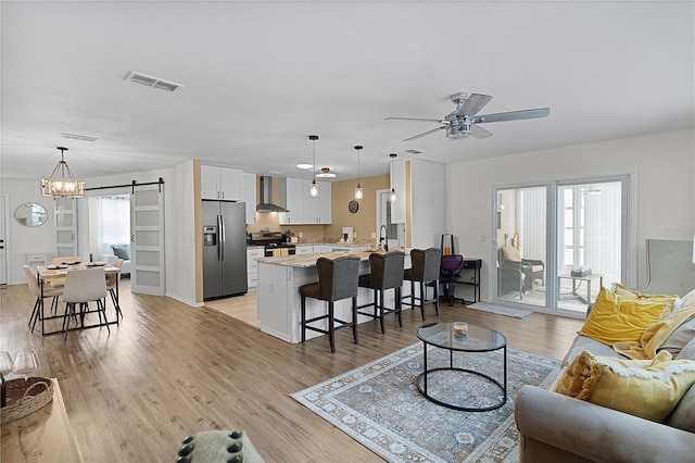 living area with a barn door, a ceiling fan, and light wood-type flooring