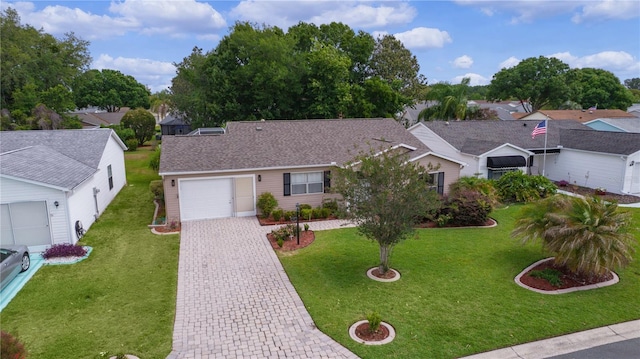 single story home with an attached garage, a front yard, decorative driveway, and a residential view