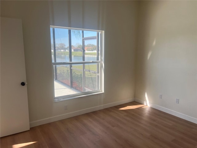 empty room with hardwood / wood-style floors and a water view