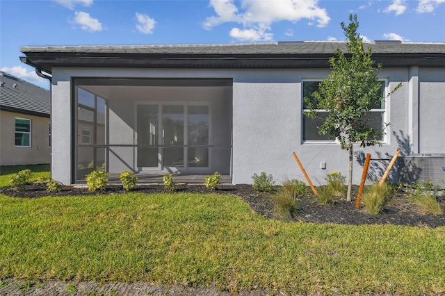 back of property with a yard and a sunroom